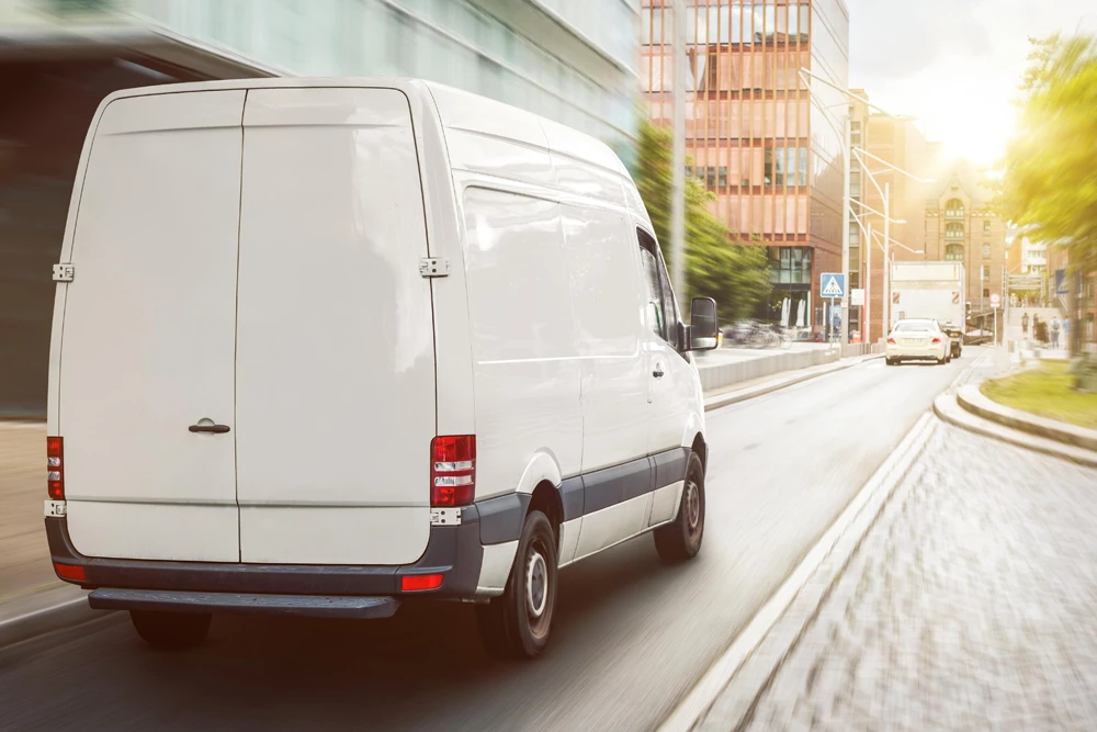 Generic delivery van traveling through a city, representing FedEx truck and delivery van accident lawyer services in Orlando Central Florida.