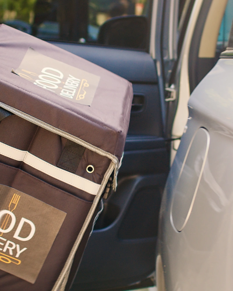 App-based food delivery driver loading an order into a personal vehicle in Central Florida
